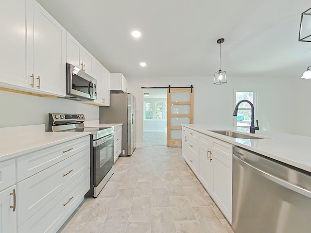 1904 Robin Rd, North Augusta, SC 29841 - kitchen with appliances with stainless steel finishes, a barn door, light countertops, white cabinetry, and decorative light fixtures