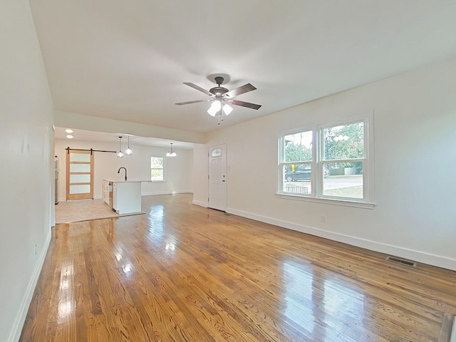 1904 Robin Rd, North Augusta, SC 29841 - unfurnished living room featuring a barn door, light wood-type flooring, and ceiling fan