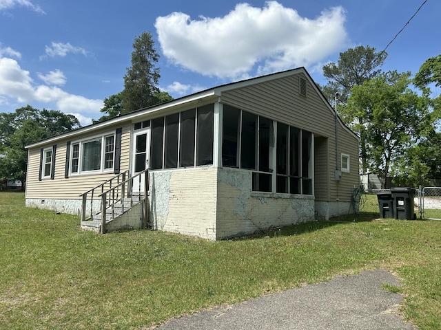 view of property exterior featuring a lawn, a sunroom, crawl space, and fence
