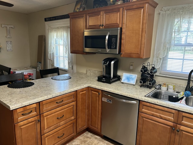 kitchen featuring a sink, a peninsula, stainless steel appliances, and light countertops
