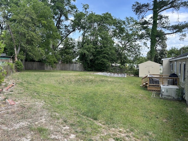 view of yard featuring fence, a storage unit, and an outbuilding