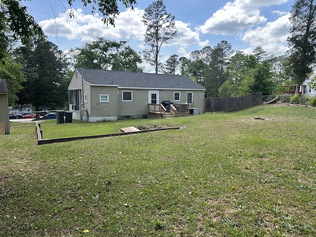 back of property with fence, a yard, crawl space, and central AC