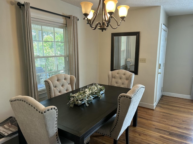 dining space with a textured ceiling, wood finished floors, a notable chandelier, and baseboards