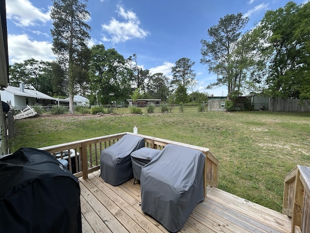 wooden deck featuring area for grilling, a fenced backyard, and a yard