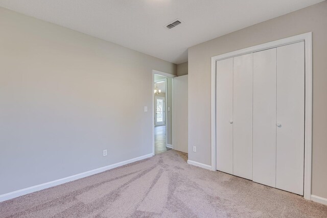 unfurnished bedroom with a closet, visible vents, carpet flooring, and baseboards