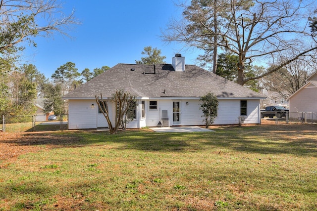 rear view of property featuring a patio, a yard, a fenced backyard, and a chimney