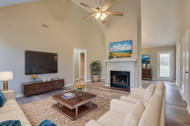 living area featuring visible vents, a fireplace with raised hearth, baseboards, and wood finished floors