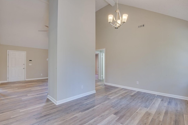 empty room with visible vents, baseboards, light wood-style floors, beamed ceiling, and a notable chandelier