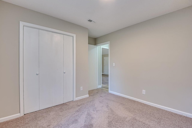 unfurnished bedroom with carpet flooring, visible vents, baseboards, and a closet