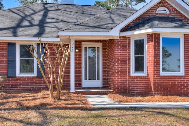 property entrance with brick siding and a shingled roof