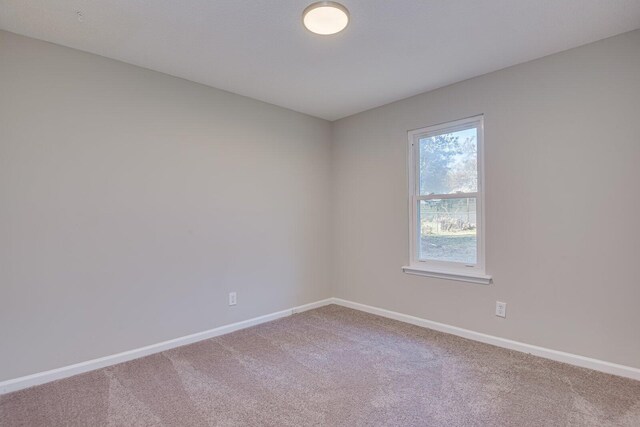 carpeted empty room featuring baseboards