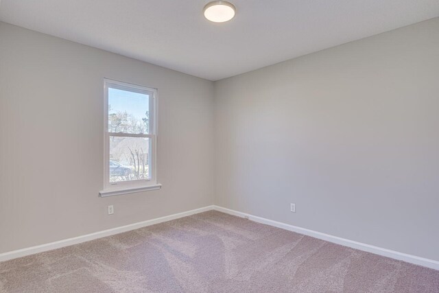 spare room featuring carpet flooring and baseboards