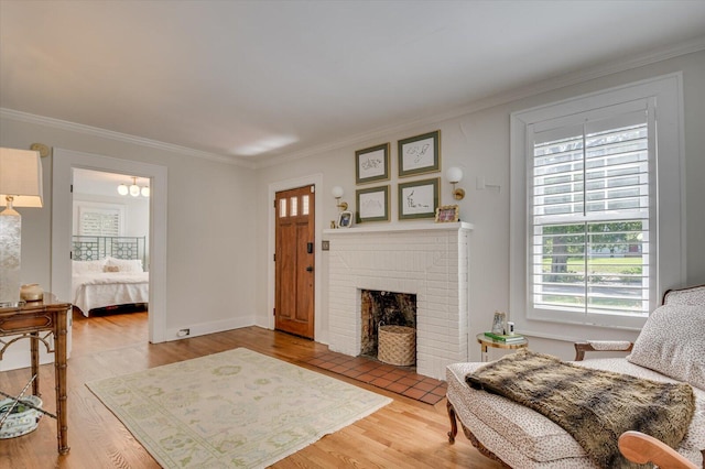 living room with a brick fireplace, crown molding, baseboards, and wood finished floors