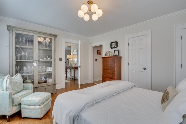 bedroom with an inviting chandelier, crown molding, baseboards, and wood finished floors