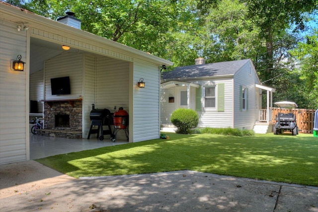 exterior space featuring a patio area, a yard, a chimney, and an outdoor stone fireplace