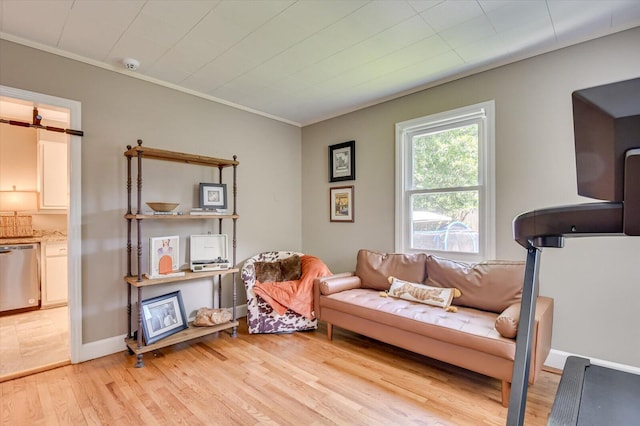 sitting room featuring light wood-style flooring, ornamental molding, and baseboards