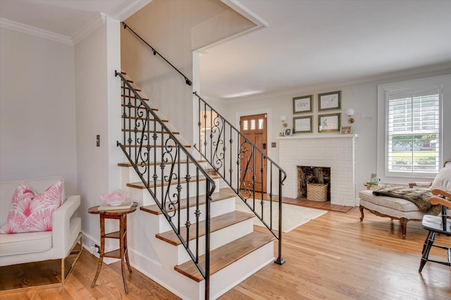 stairway with crown molding, a fireplace, and wood finished floors