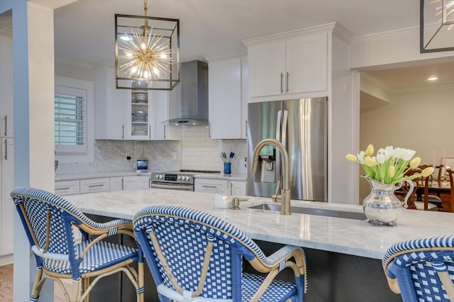 kitchen with appliances with stainless steel finishes, white cabinetry, crown molding, and wall chimney range hood