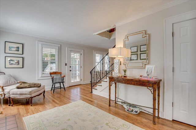 foyer entrance featuring stairs, ornamental molding, wood finished floors, and baseboards