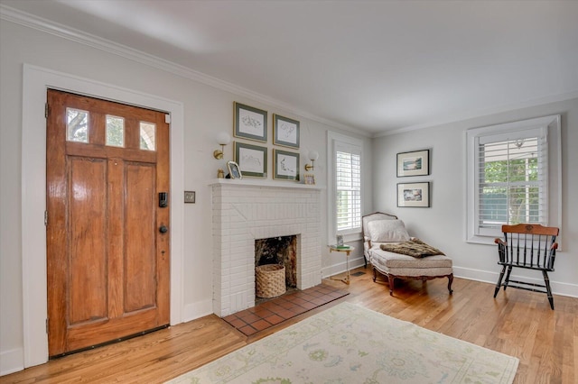 foyer entrance with a brick fireplace, a healthy amount of sunlight, crown molding, and wood finished floors