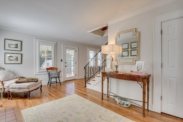 entrance foyer featuring wood finished floors, crown molding, baseboards, and stairs