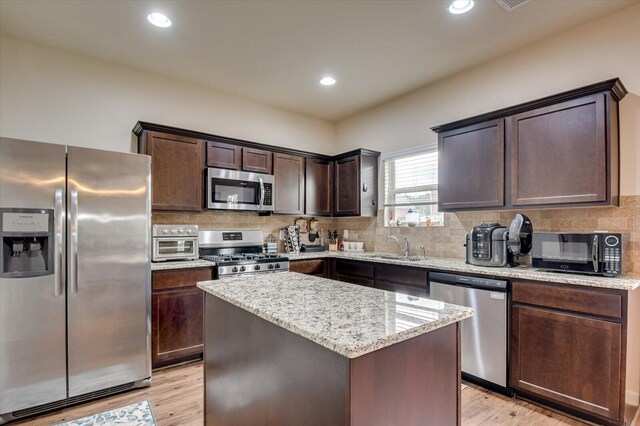 kitchen featuring a center island, sink, dark brown cabinets, light hardwood / wood-style floors, and stainless steel appliances