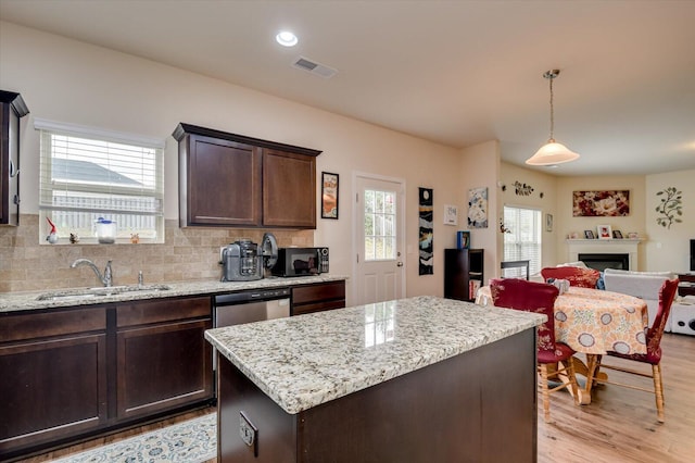 kitchen with dark brown cabinetry, sink, a center island, stainless steel dishwasher, and pendant lighting