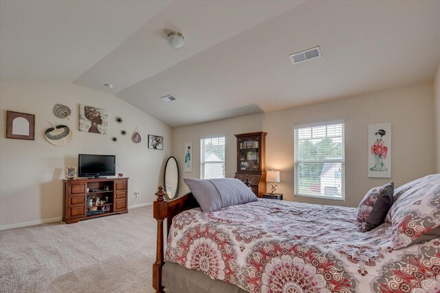 bedroom with light colored carpet and lofted ceiling