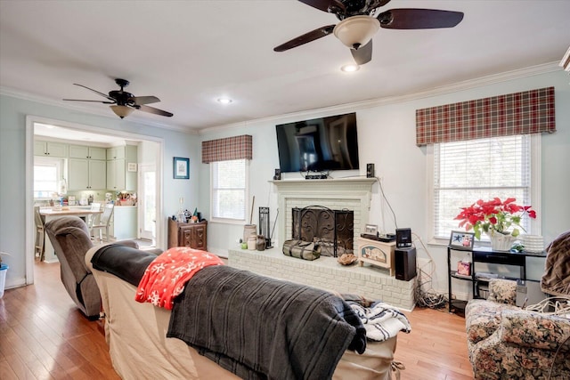 living room featuring wood-type flooring, a fireplace, ornamental molding, and plenty of natural light