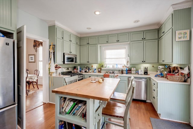 kitchen with stainless steel appliances, green cabinetry, light hardwood / wood-style floors, and a kitchen island