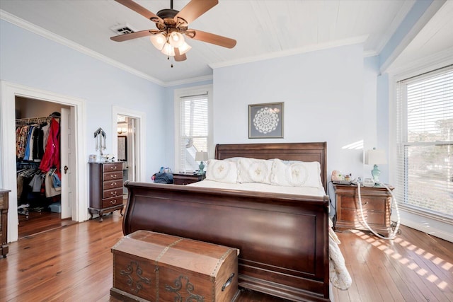 bedroom with ceiling fan, crown molding, wood-type flooring, and multiple windows