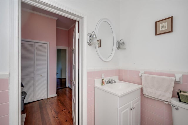 bathroom featuring tile walls, ornamental molding, hardwood / wood-style flooring, toilet, and vanity