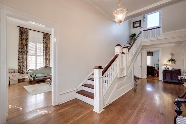 stairway featuring hardwood / wood-style floors, a healthy amount of sunlight, and ornamental molding