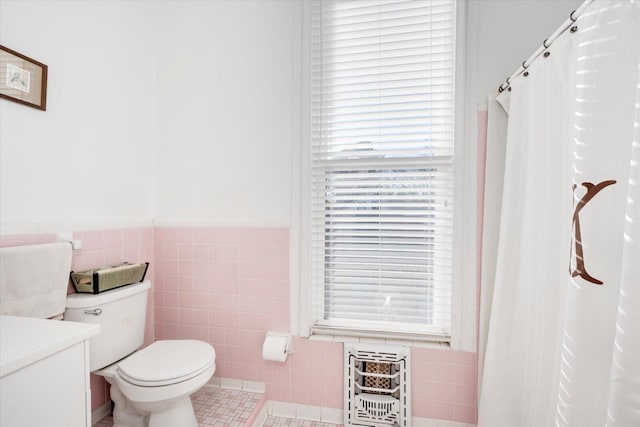 bathroom featuring tile walls, toilet, tile patterned floors, heating unit, and vanity