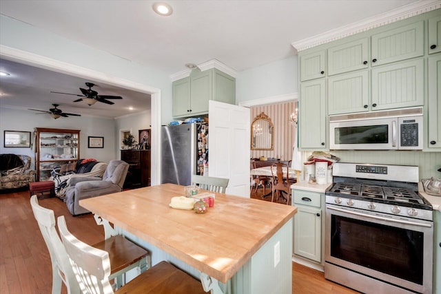 kitchen with stainless steel appliances, green cabinetry, a breakfast bar, light wood-type flooring, and ceiling fan