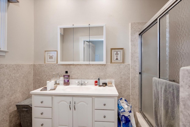 bathroom featuring a shower with door, vanity, and tile walls