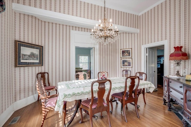 dining area featuring light wood-type flooring, crown molding, and a chandelier