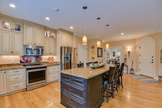 2051 Waterbridge Ln, Aiken, SC 29803 - kitchen featuring stainless steel appliances, cream cabinetry, a breakfast bar, a kitchen island, and light wood-style flooring