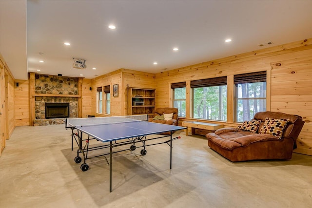 recreation room featuring a fireplace and wooden walls