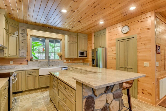 kitchen featuring wooden walls, a center island, stainless steel appliances, and light stone counters