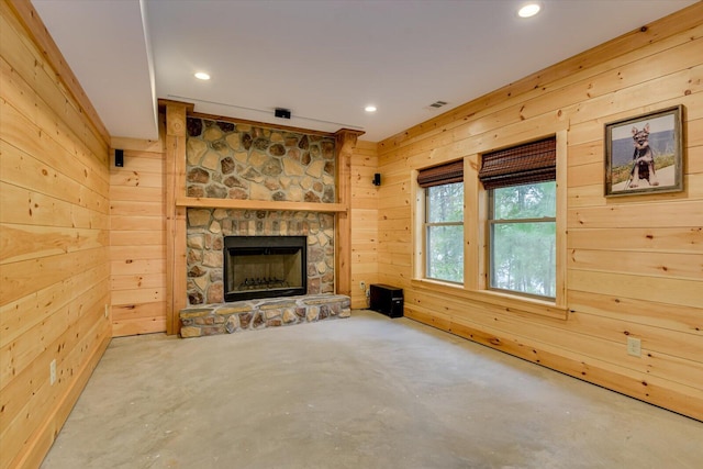 unfurnished living room featuring a stone fireplace and wooden walls