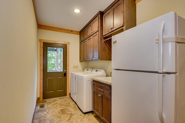 washroom featuring washing machine and dryer, cabinets, and ornamental molding