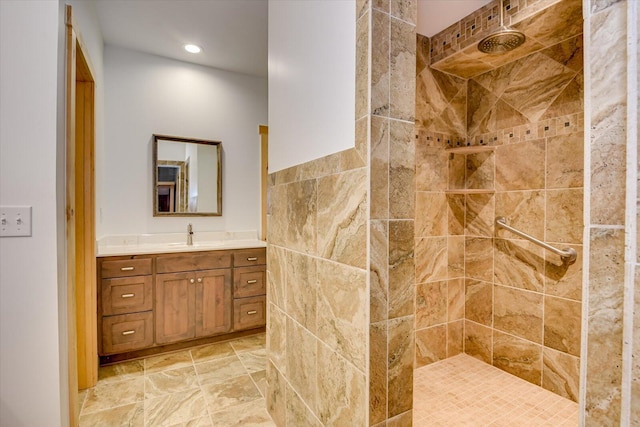 bathroom with tiled shower, vanity, and tile walls