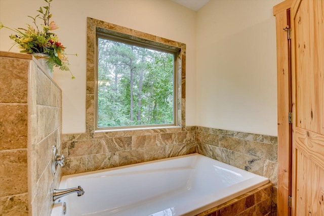 bathroom featuring a relaxing tiled tub and a healthy amount of sunlight