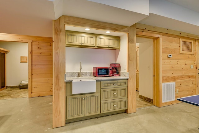 kitchen featuring green cabinets, wooden walls, and sink