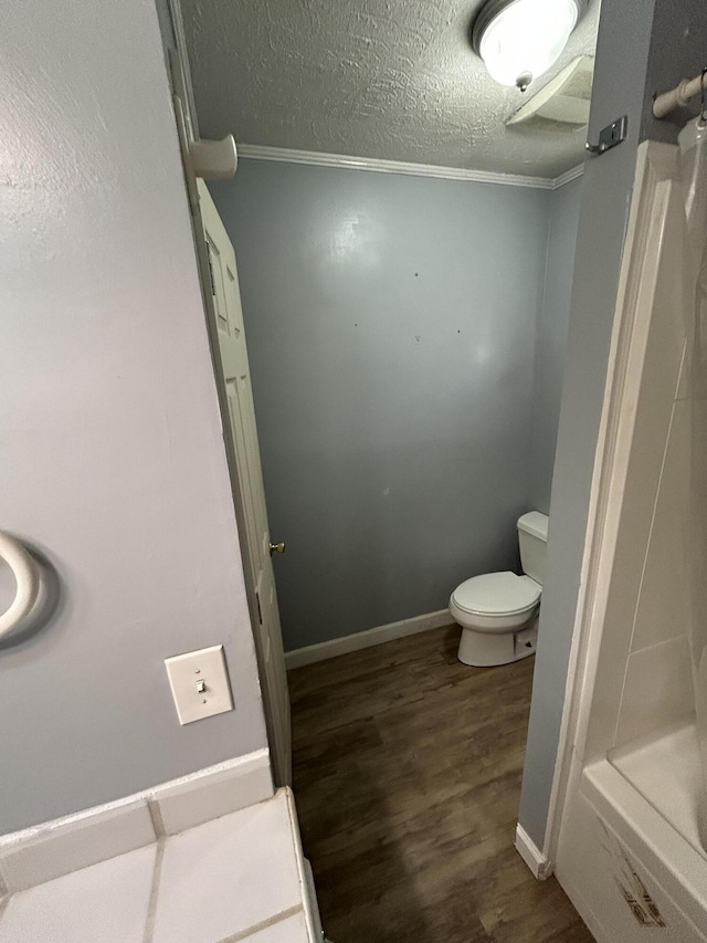 full bathroom featuring toilet, a shower, wood finished floors, a textured ceiling, and baseboards