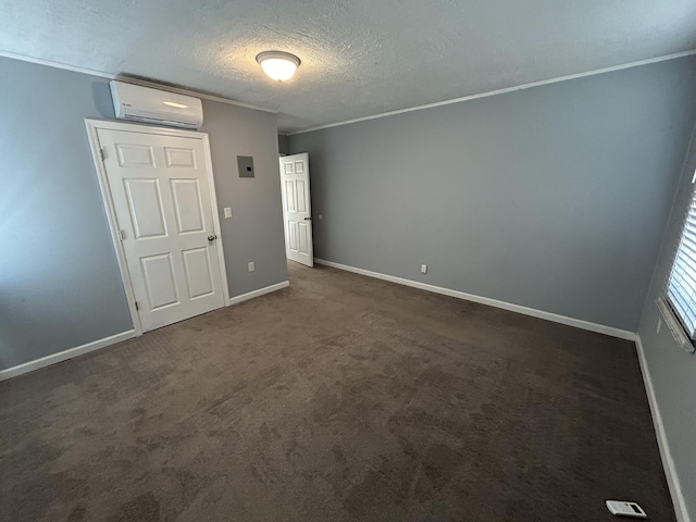 unfurnished bedroom with a wall unit AC, dark carpet, crown molding, a textured ceiling, and baseboards