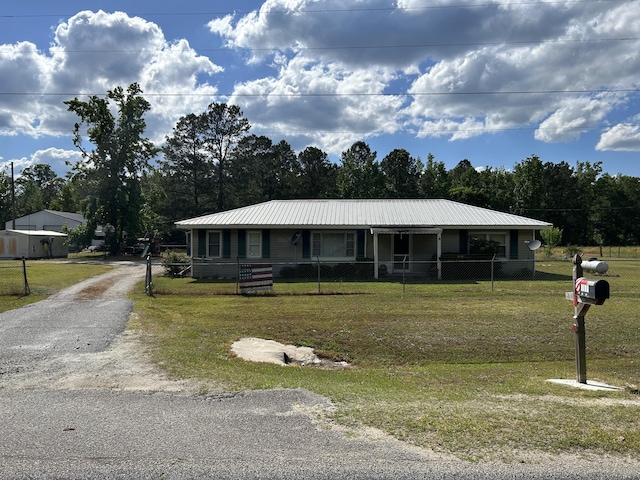 view of front of house with a front lawn, driveway, fence private yard, and metal roof