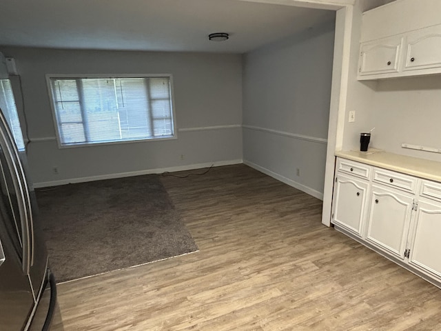 unfurnished dining area with light wood finished floors and baseboards