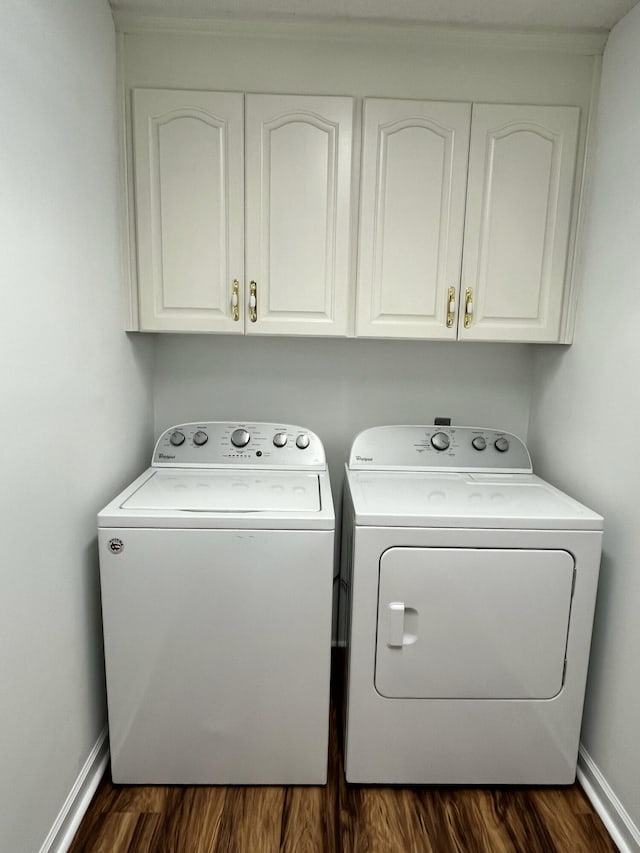 clothes washing area featuring cabinet space, washing machine and dryer, baseboards, and dark wood finished floors